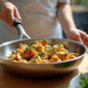 Chef sautant des girolles fraîches avec des herbes dans une poêle en inox