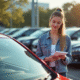 Jeune femme inspectant une Peugeot 208 d'occasion en concession