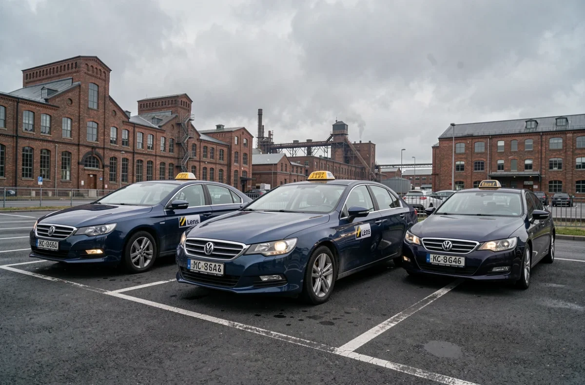 Flotte de taxis bleus du GIE Lens Taxis alignés dans un parking urbain de la ville de Lens